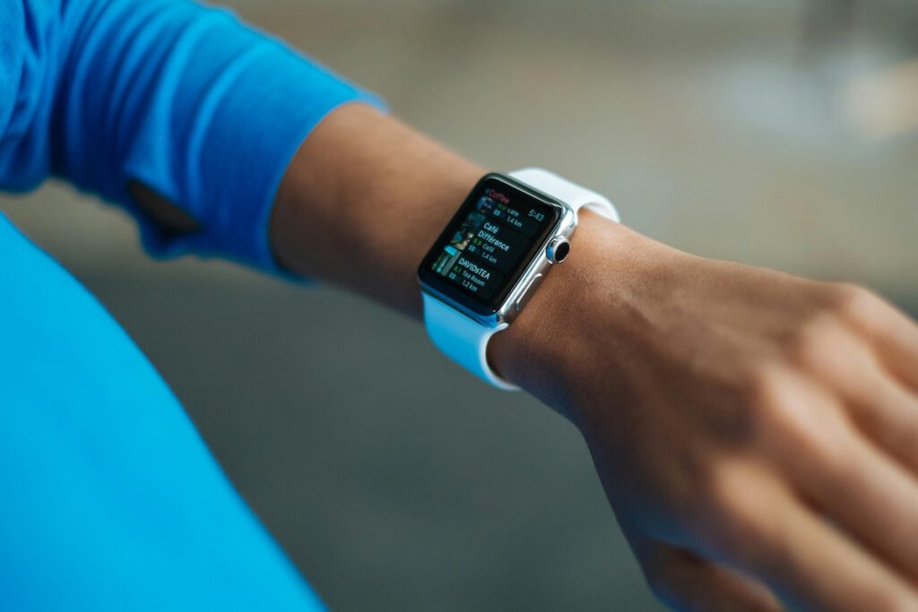 Nahaufnahme einer Smartwatch mit weißem Armband am Handgelenk – symbolisch für Fitness-Gadgets.